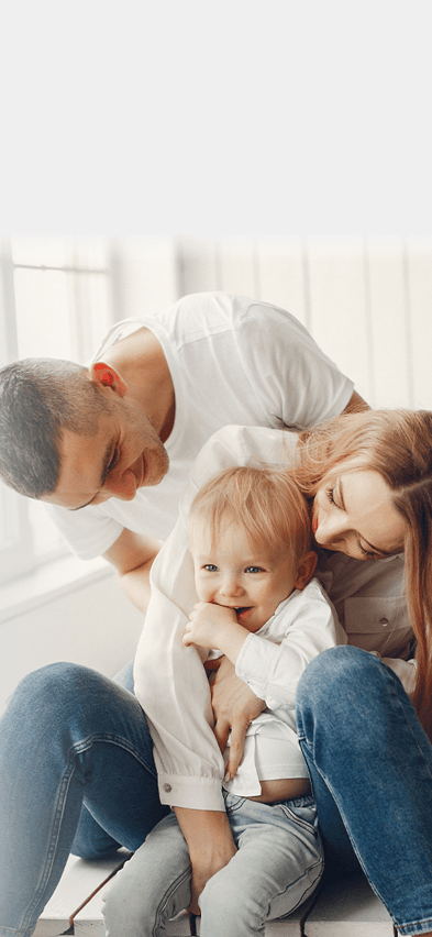 Um homem, uma mulher e uma criança estão sentados em um banco, todos estão sorrindo.